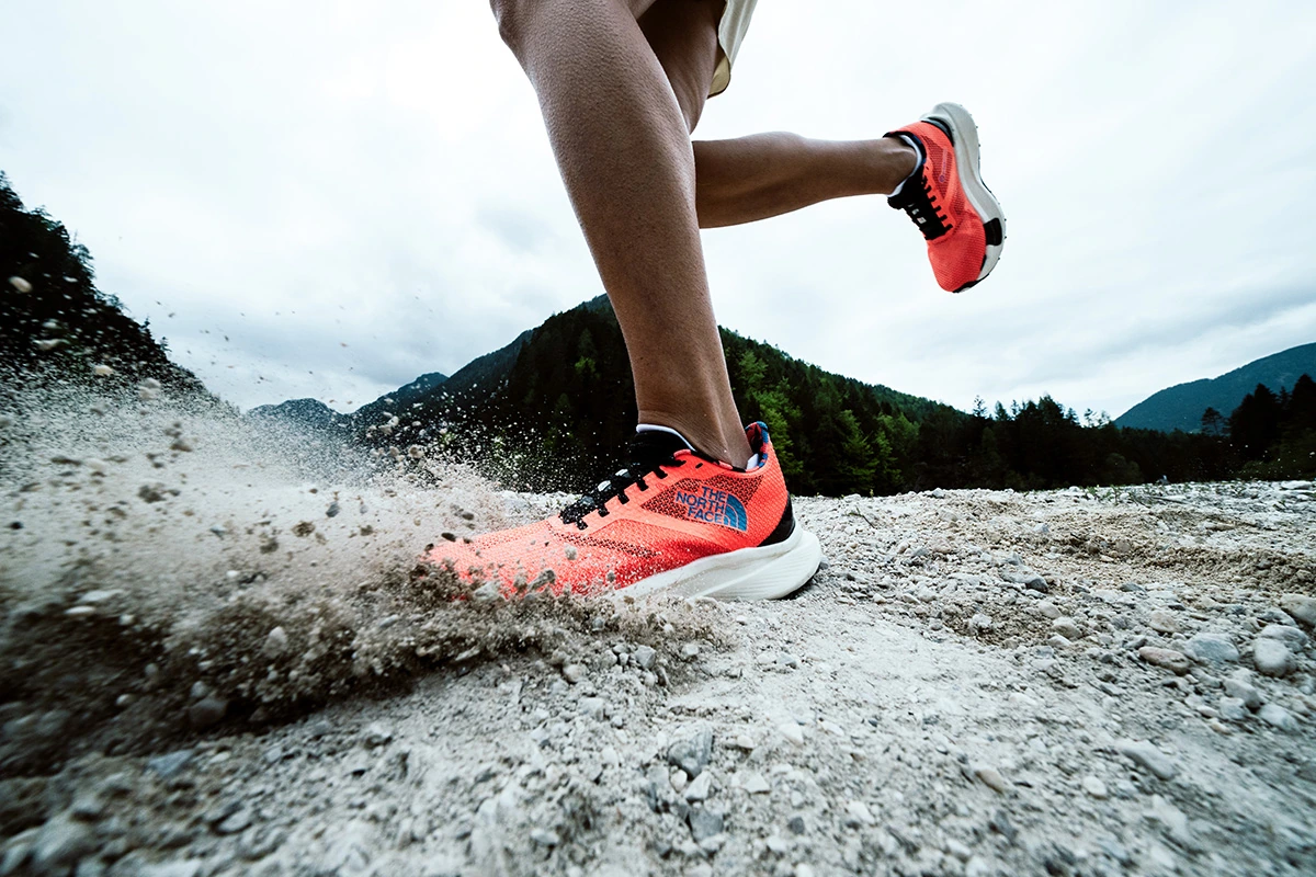 Runner wearing red Summit VECTIV Pro shoes on loose mountain gravel, photographed for The North Face in 2023.