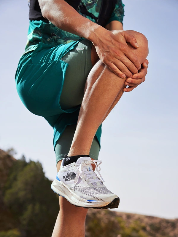 Runner stretching in a white VECTIV Enduris 3 shoe with blue details.