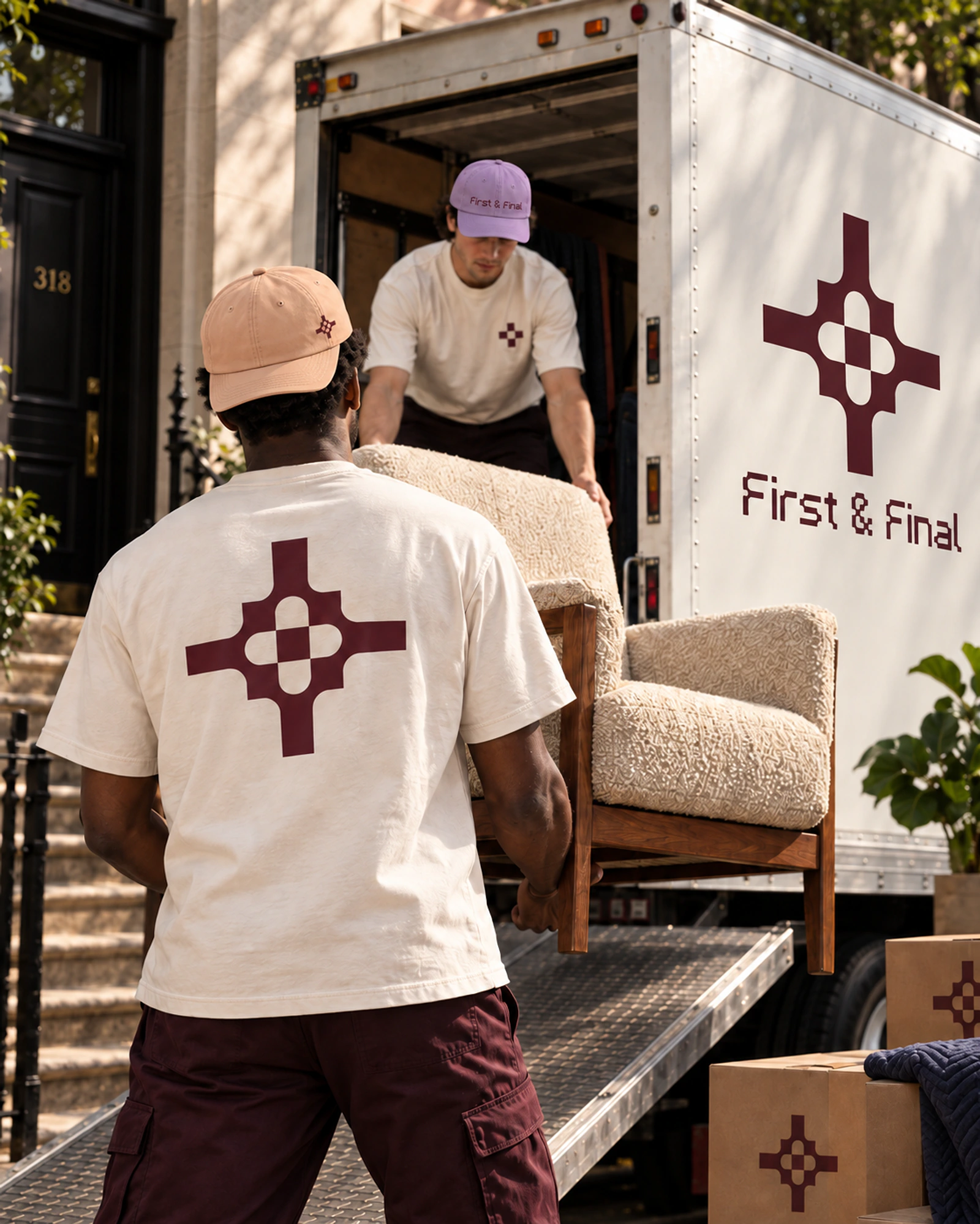 Two crew members unloading an upholstered chair from a First & Final box truck