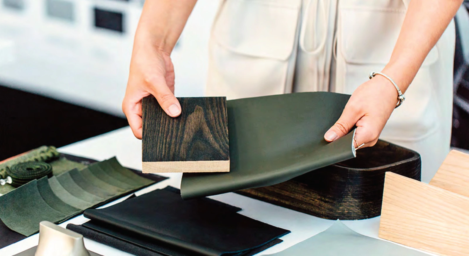 Hands comparing green upholstery and wood samples during Rivian color, material and finish development.