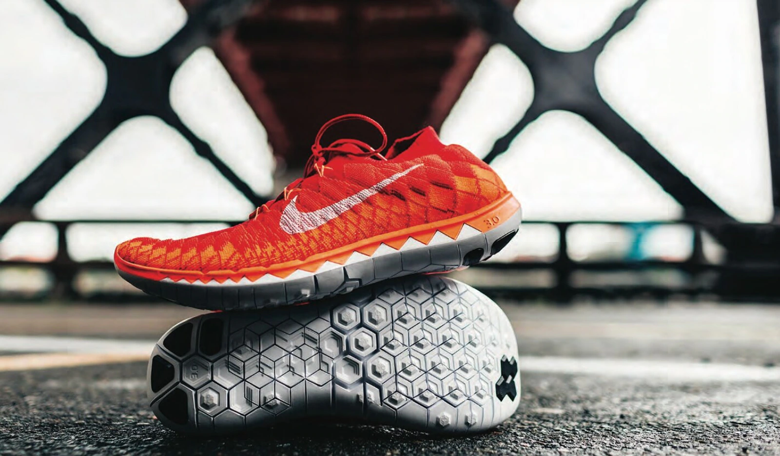 Orange Nike running shoe balanced on a geometric flexible outsole.