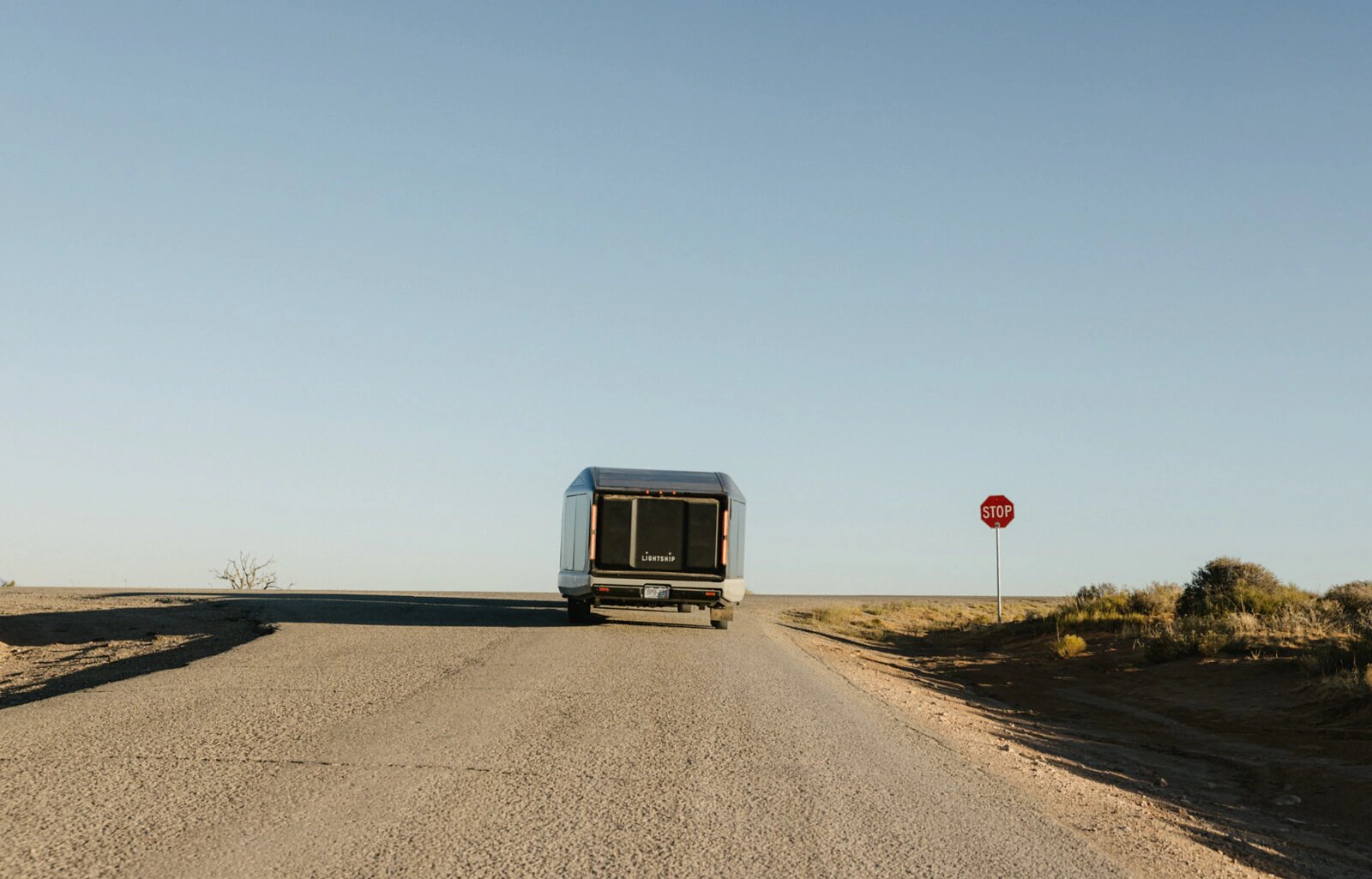 Lightship trailer on a minimal open road beneath a clear blue sky.