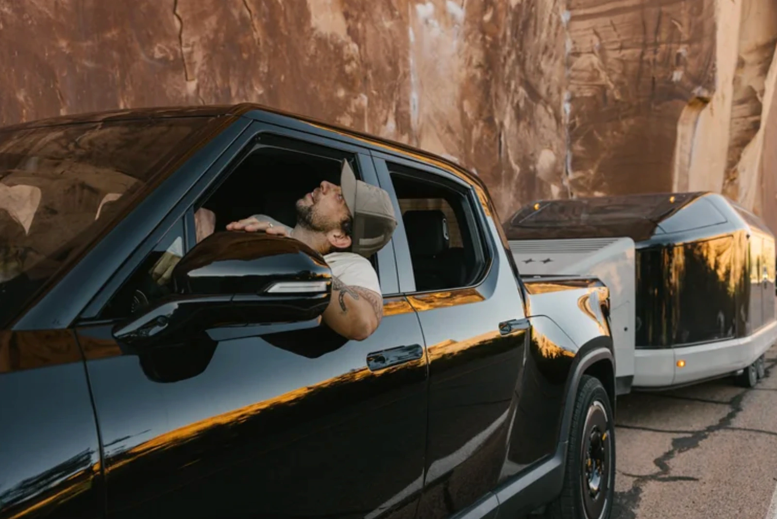 A Rivian truck towing the Lightship trailer through a canyon road.