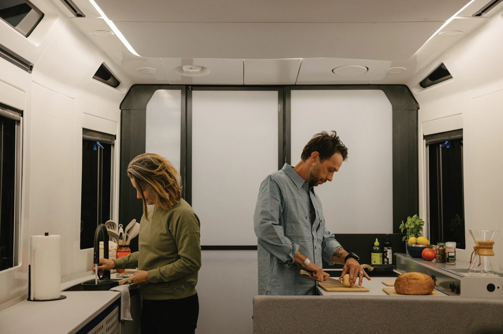 Two people preparing food inside the Lightship trailer kitchen.