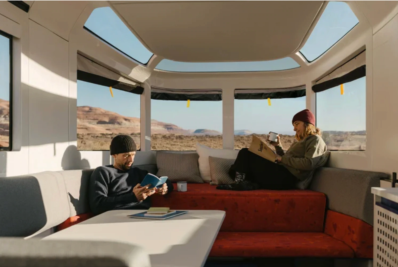 Two people relaxing inside the Lightship trailer lounge in a desert setting.