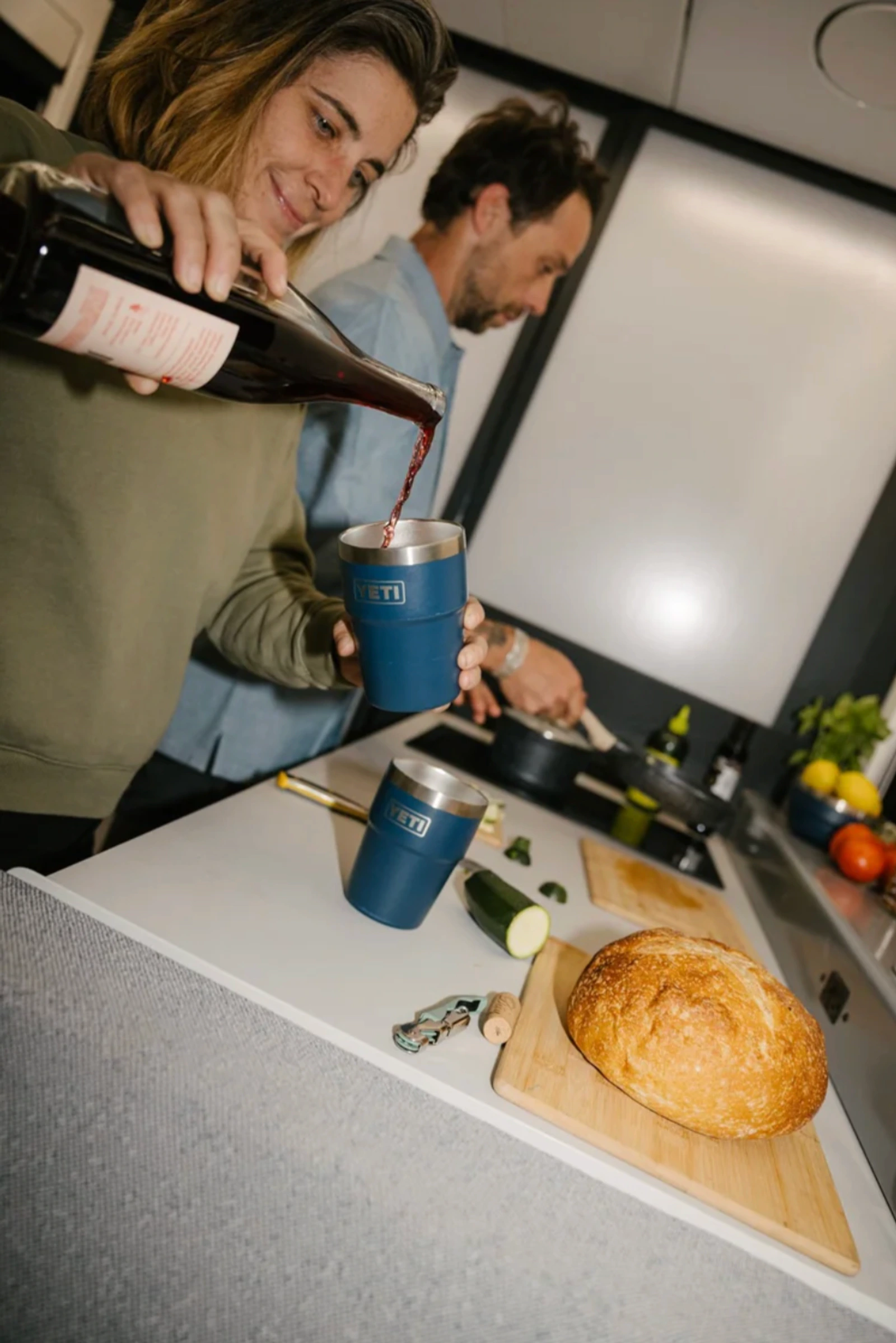 Two people preparing a meal inside the Lightship trailer kitchen.