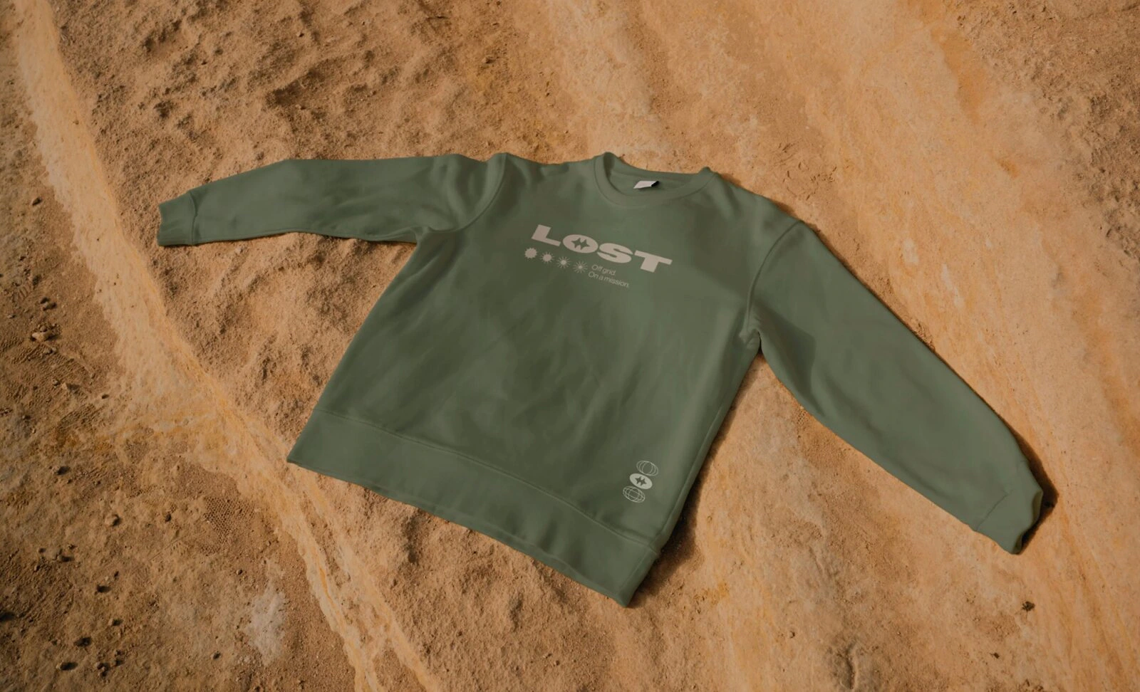 Green L.O.S.T. sweatshirt laid on desert rock.