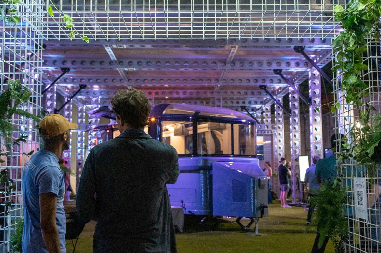Visitors looking into the Lightship SXSW 2023 installation through the planted modular entrance.
