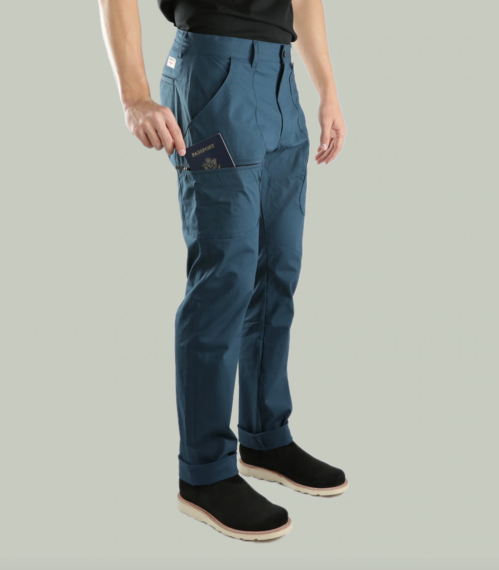 Front three-quarter studio view of Terrascout blue utility pants with passport pocket and black slip-on footwear.