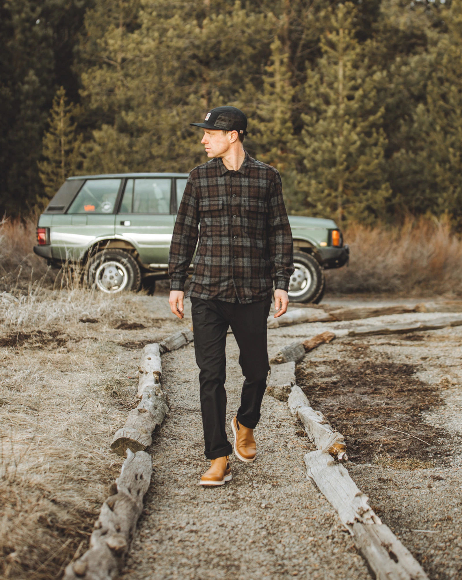 Terrascout apparel worn outdoors beside a green vintage Range Rover in a pine landscape.