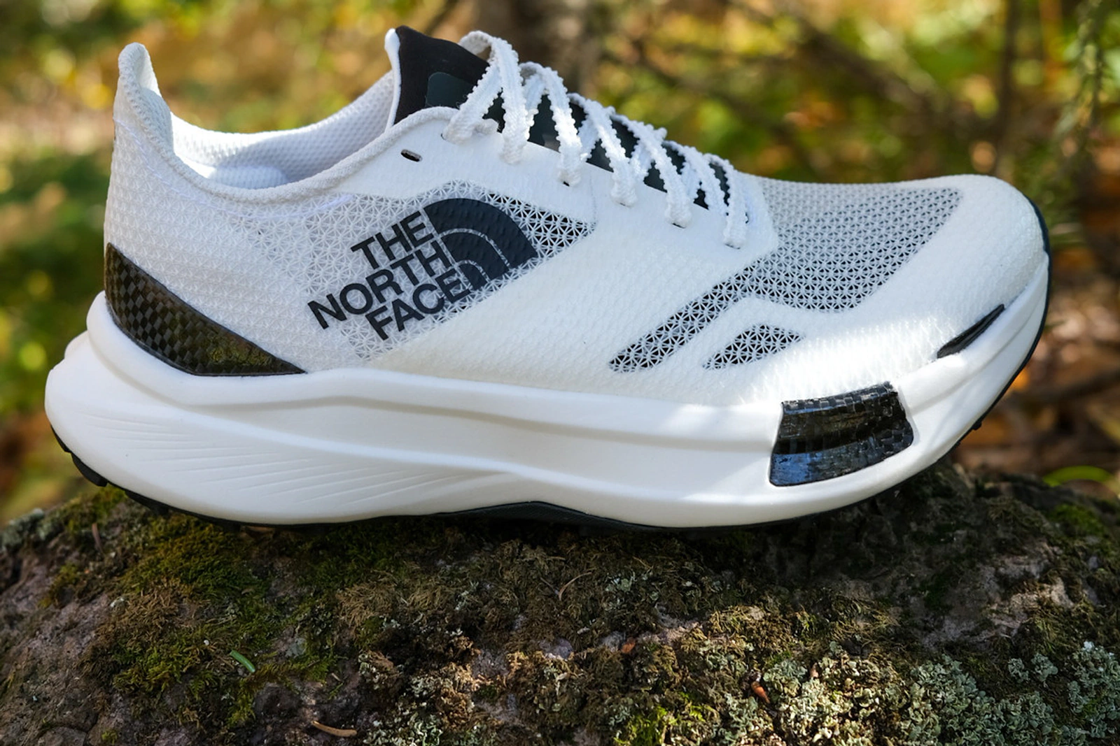 White The North Face VECTIV performance shoe photographed outdoors on moss and rock.