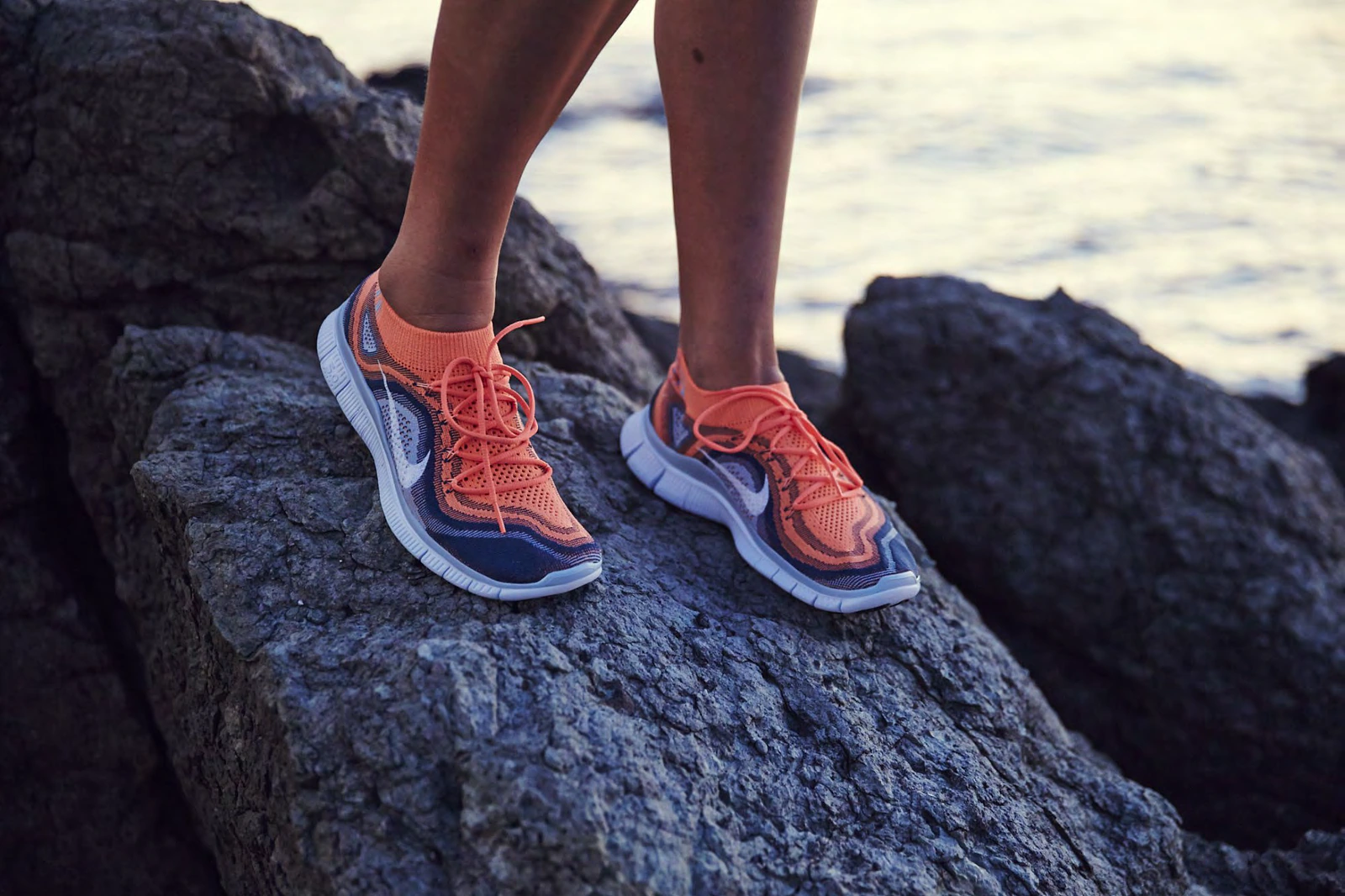Orange and blue Nike Free running shoes worn outdoors.