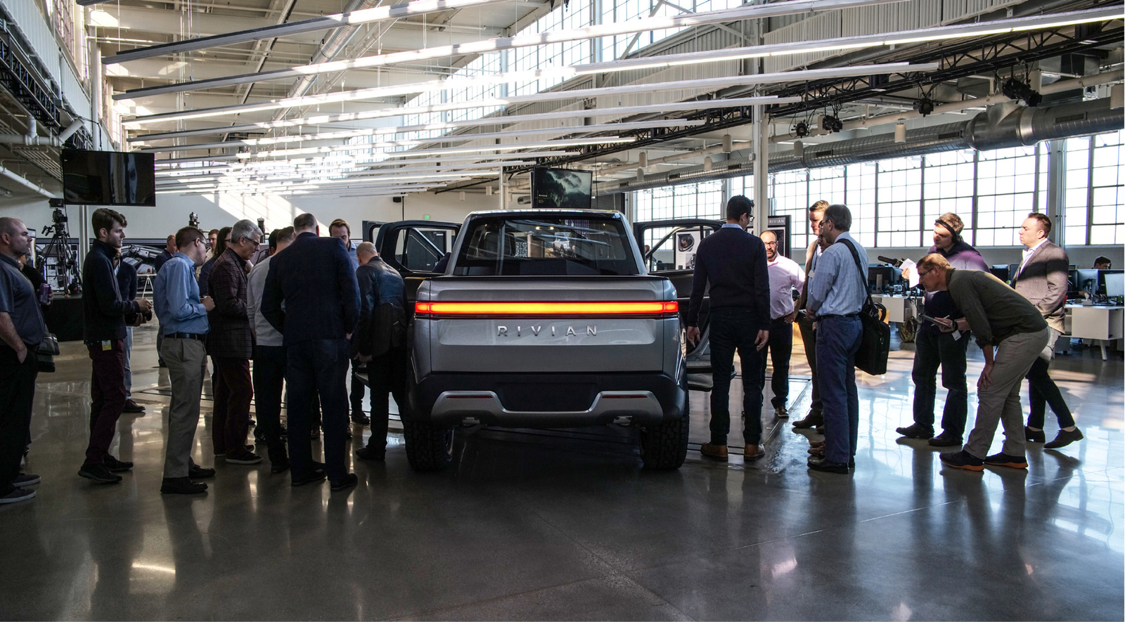 Guests gathered around the R1T in Rivian’s Michigan design studio beneath the factory roof structure.