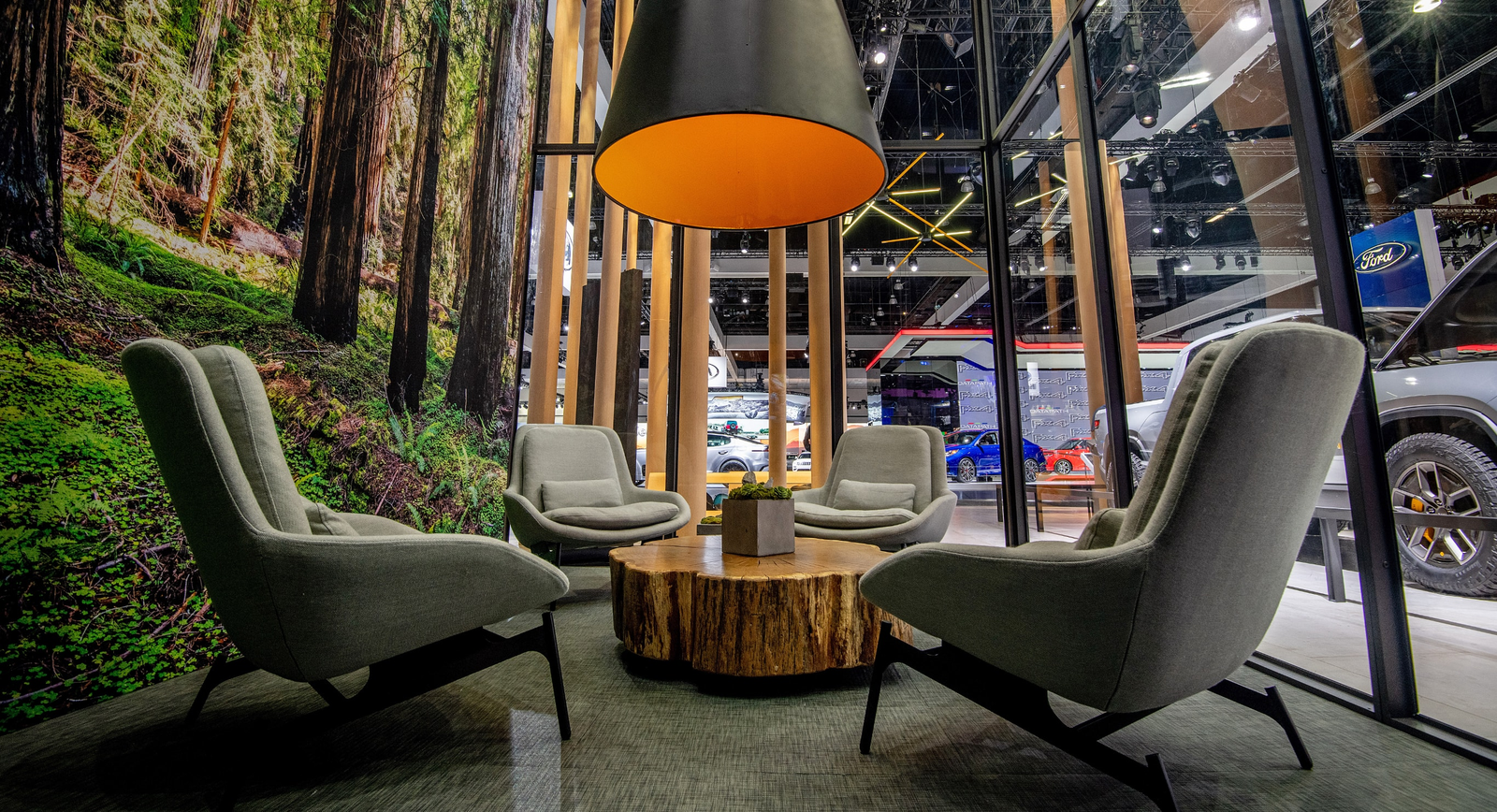 Lounge chairs, a side table and forest imagery create a gathering space within the Rivian exhibit.